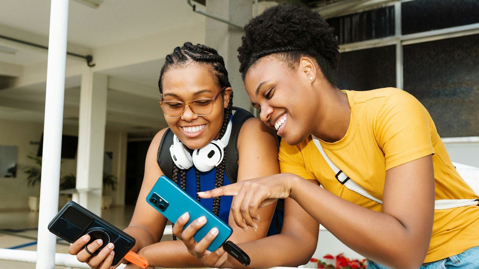 Two students laughing together while looking at their phones